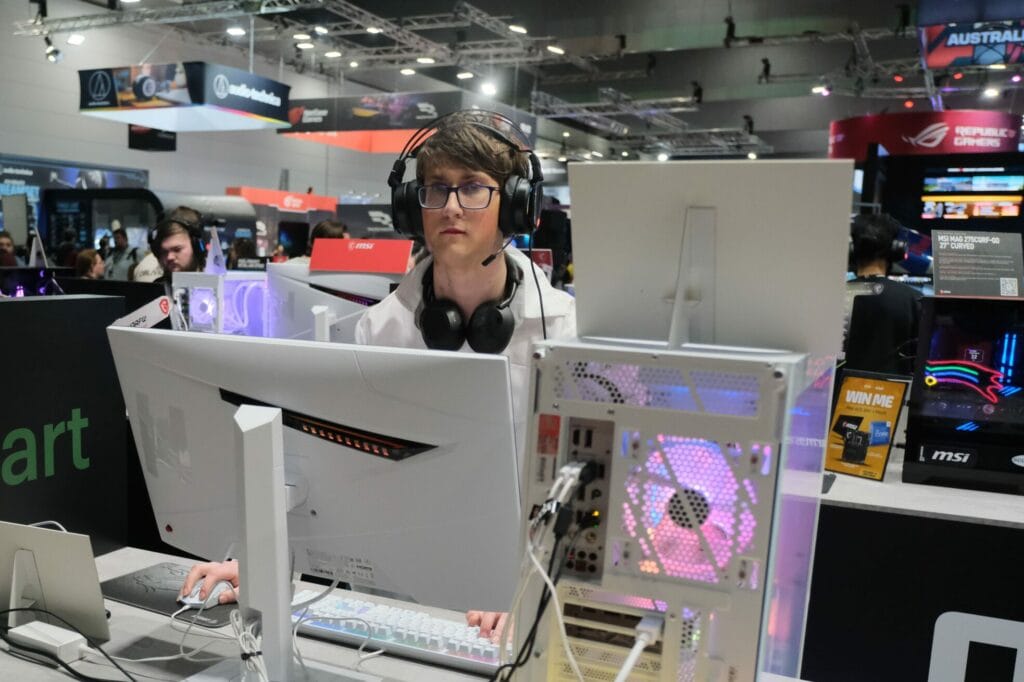 A man is working on a computer at a gaming convention.