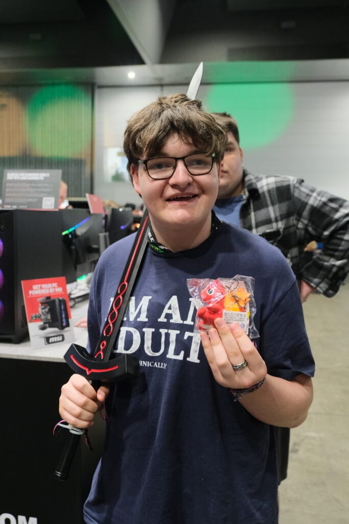 A young man showcasing his independence skills by wielding a sword while operating a computer.